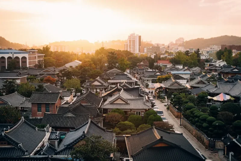 Traditional Korean rooftops and a city skyline in warm evening light
